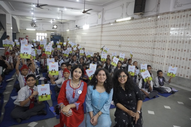 Sanya Ghai with colleagues and school students holding educational booklets at a Pratisandhi workshop